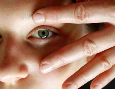 On voit sur l’image une jeune femme qui reçoit un massage Kobido. Le zoom est fait sur l’œil gauche. La partie du contour de l’œil est massée délicatement entre l’index et le majeur dans un mouvement qui part de l’intérieur de l’œil en direction de la tempe.